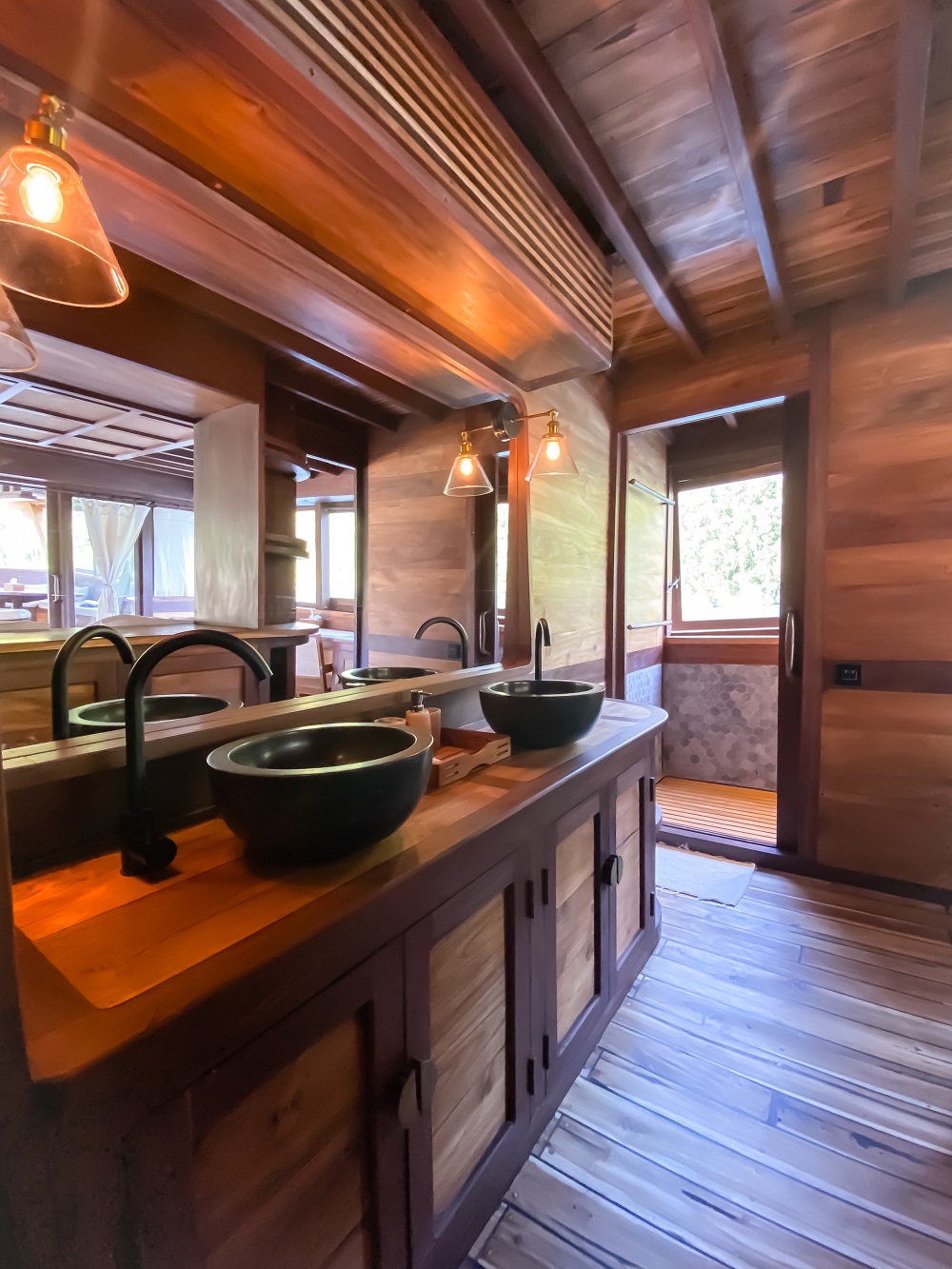 Master ensuite on Senja with twin stone basins, teak counter and glass pendant lights