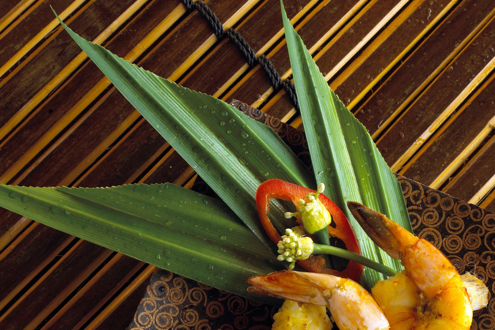 Spiced prawn skewers plated with pandan leaves on a lacquer dish aboard Silolona
