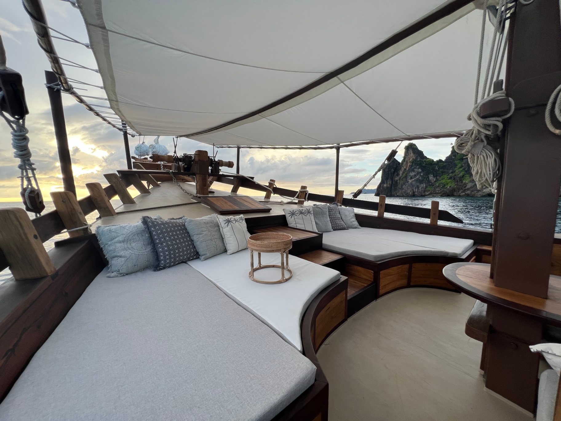 Dewata foredeck lounge cushions at sunrise with karst island beside the yacht