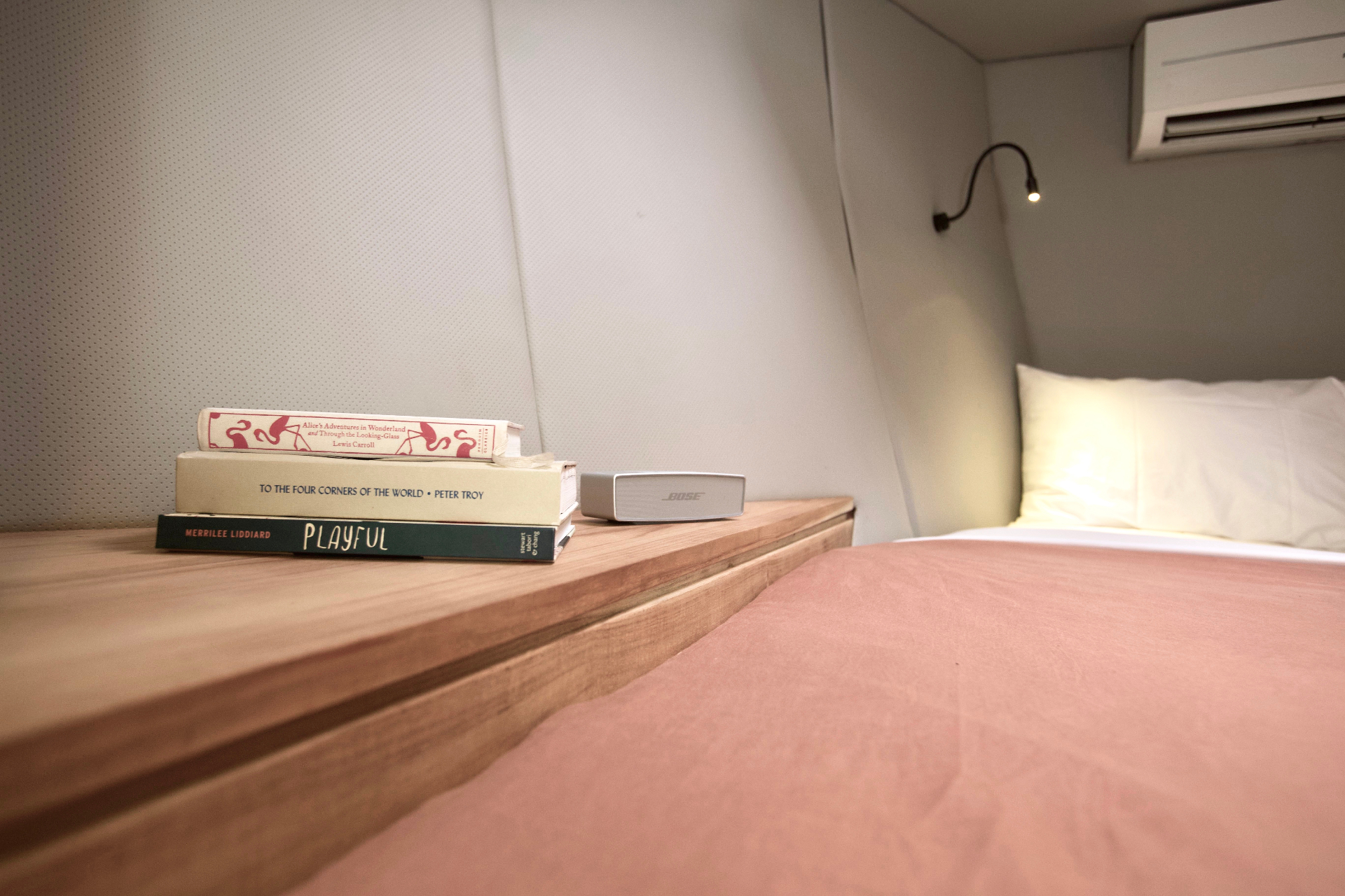 Bedside detail on Splendour with books, Bose speaker, reading light and air-conditioning above