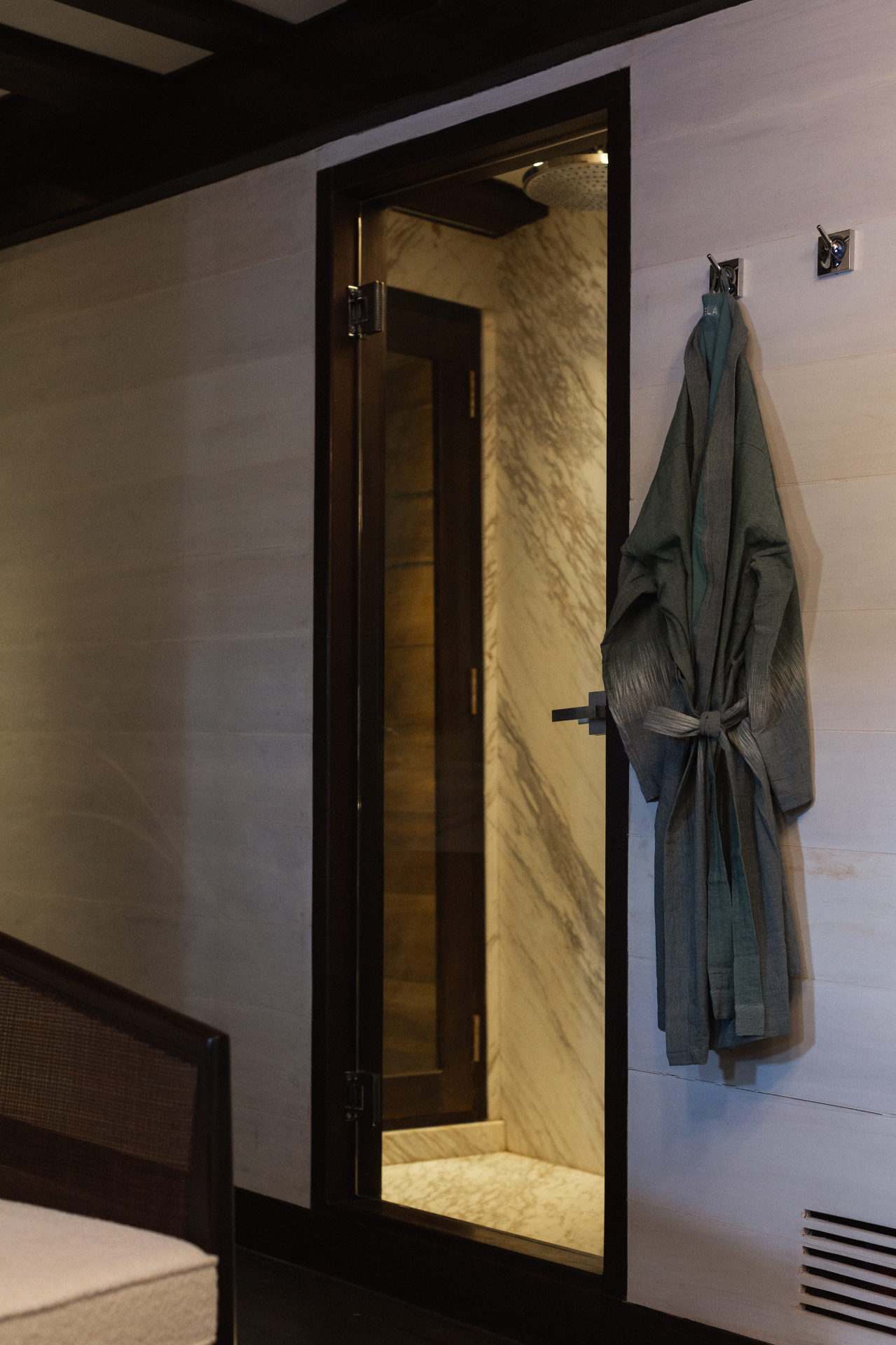 Marble rain shower in a Vela stateroom en-suite with monogrammed linen robe on chrome hooks