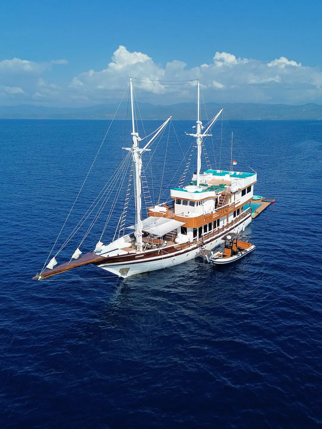Kayra Phinisi anchored on deep blue water under a bright sky
