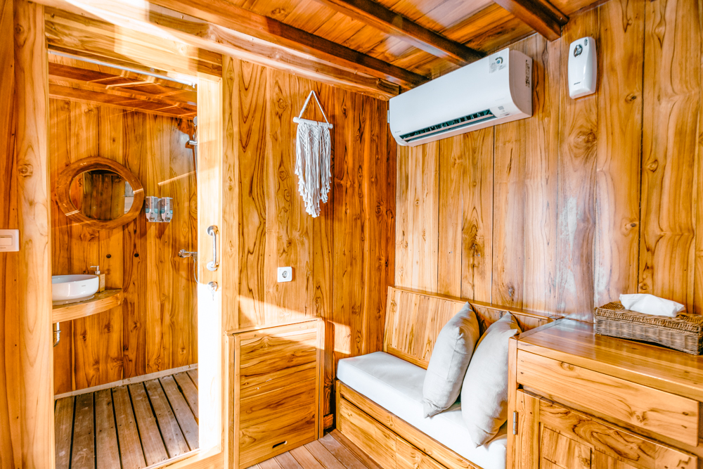 Andamari cabin sitting area with bench seat, air conditioning and open doorway into the ensuite bathroom