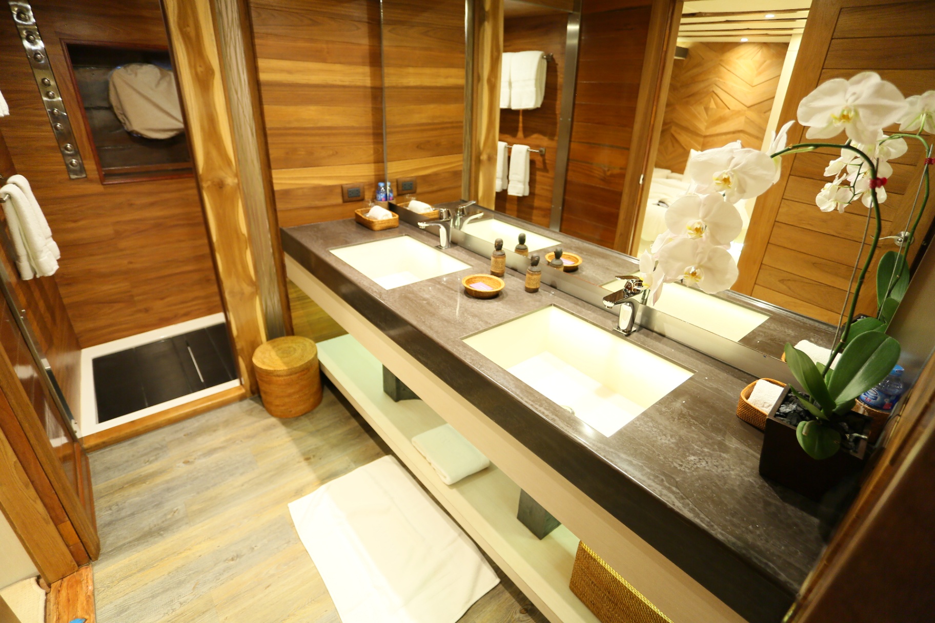 Guest ensuite on Lamima with stone vanity, walk-in shower and orchid arrangement