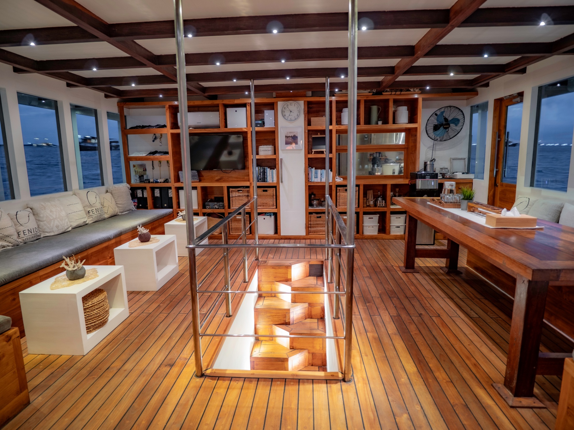 Fenides indoor salon with teak shelving, sofa seating and dining table
