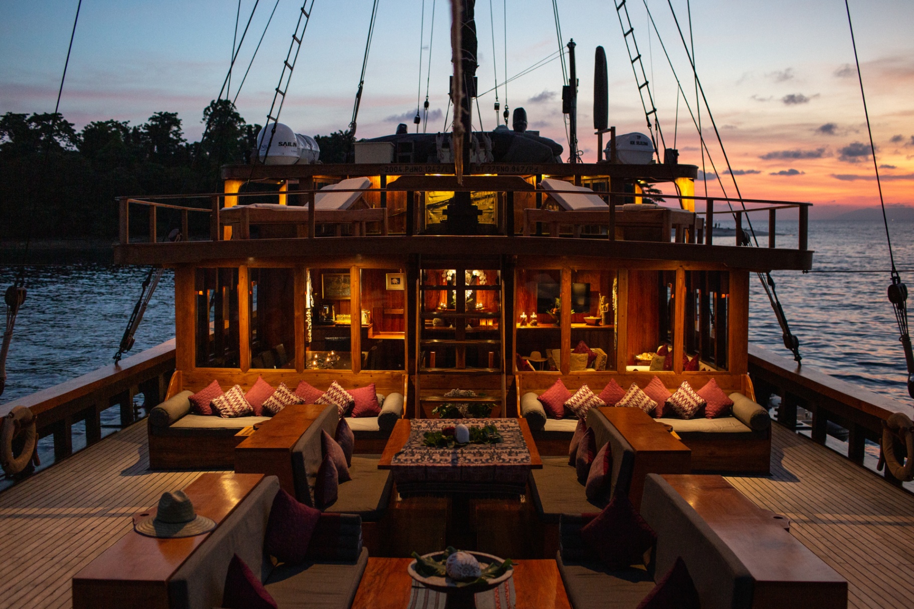 Silolona aft deck lounge lit by lanterns at sunset with ikat cushions