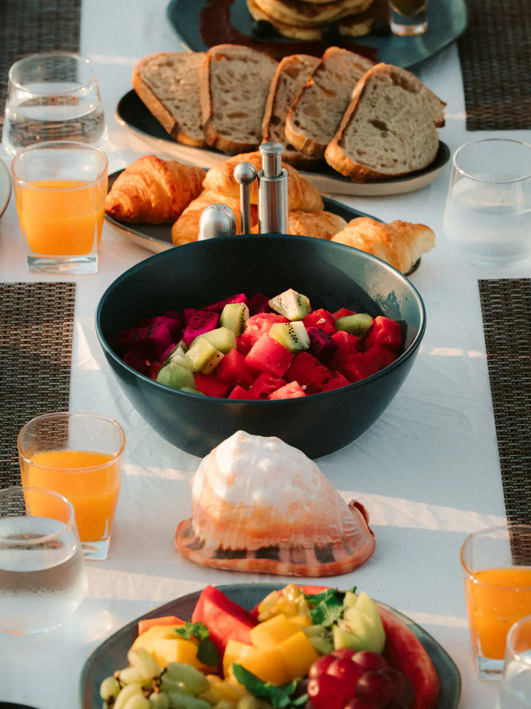 Fresh fruit bowl, croissants, sourdough and orange juice on The Oracle's breakfast table