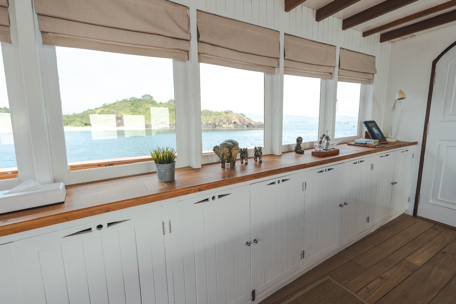 Komodo suite reading corner with teak sill, brass sculptures and picture windows framing Komodo National Park