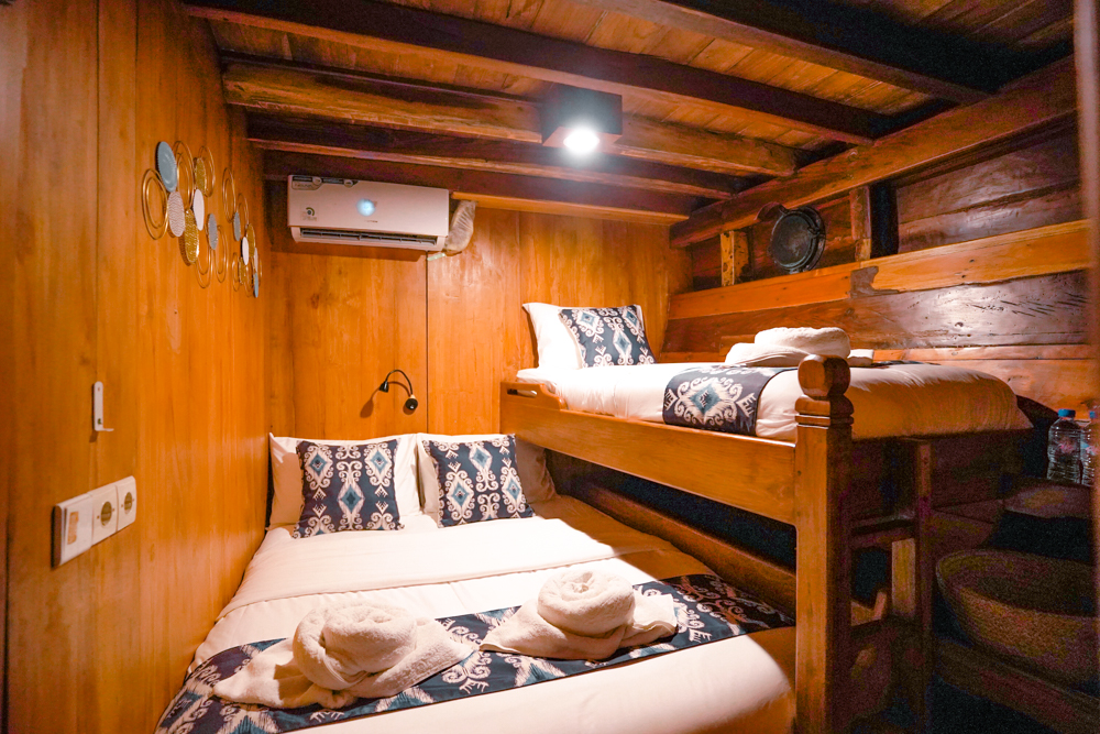 Twin cabin on Adishree with a lower double bed and upper single bunk, both dressed in ikat linens