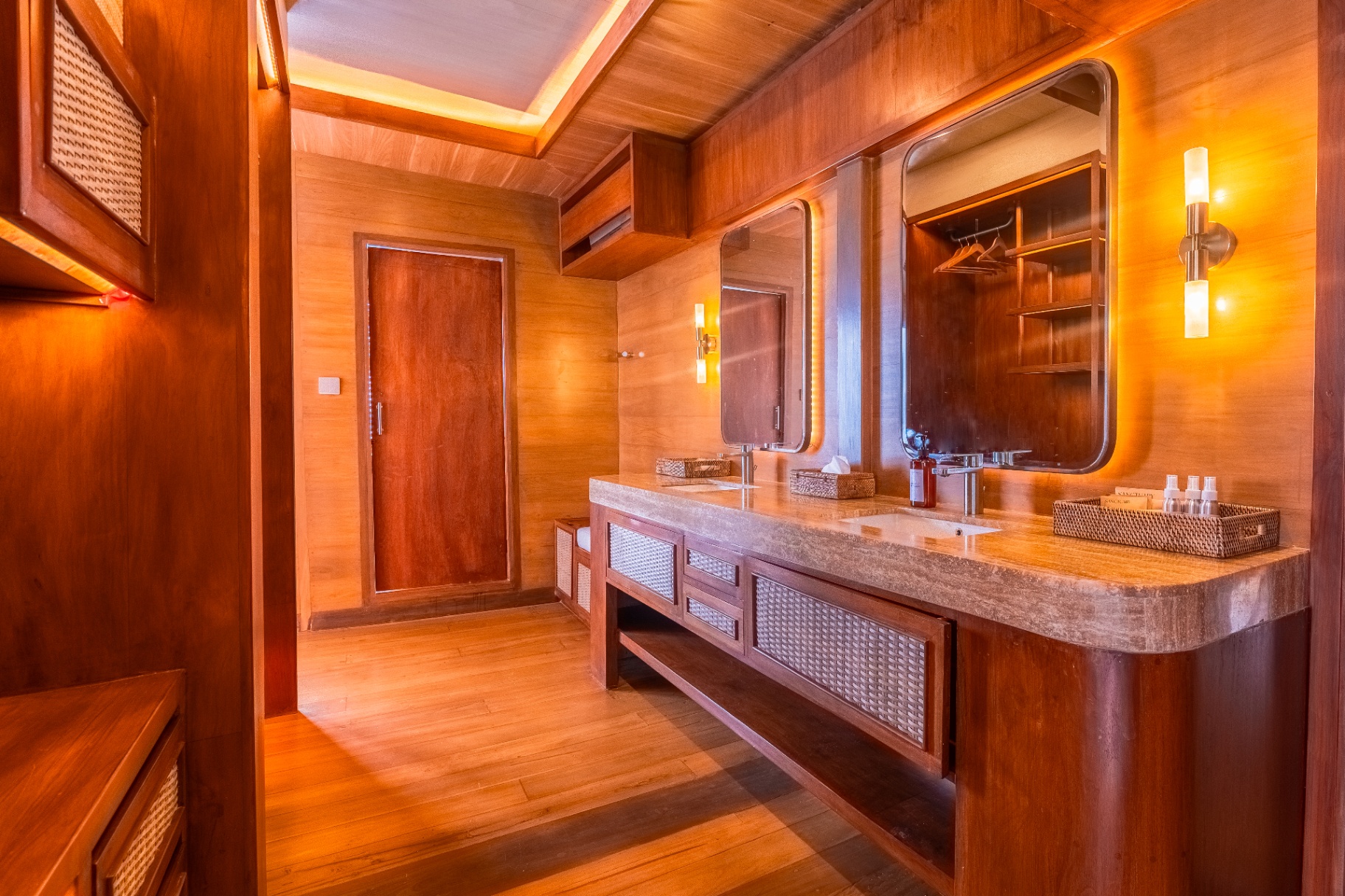 Second master ensuite view on Sanctuary with twin travertine basins, tall backlit mirrors and warm teak panelling
