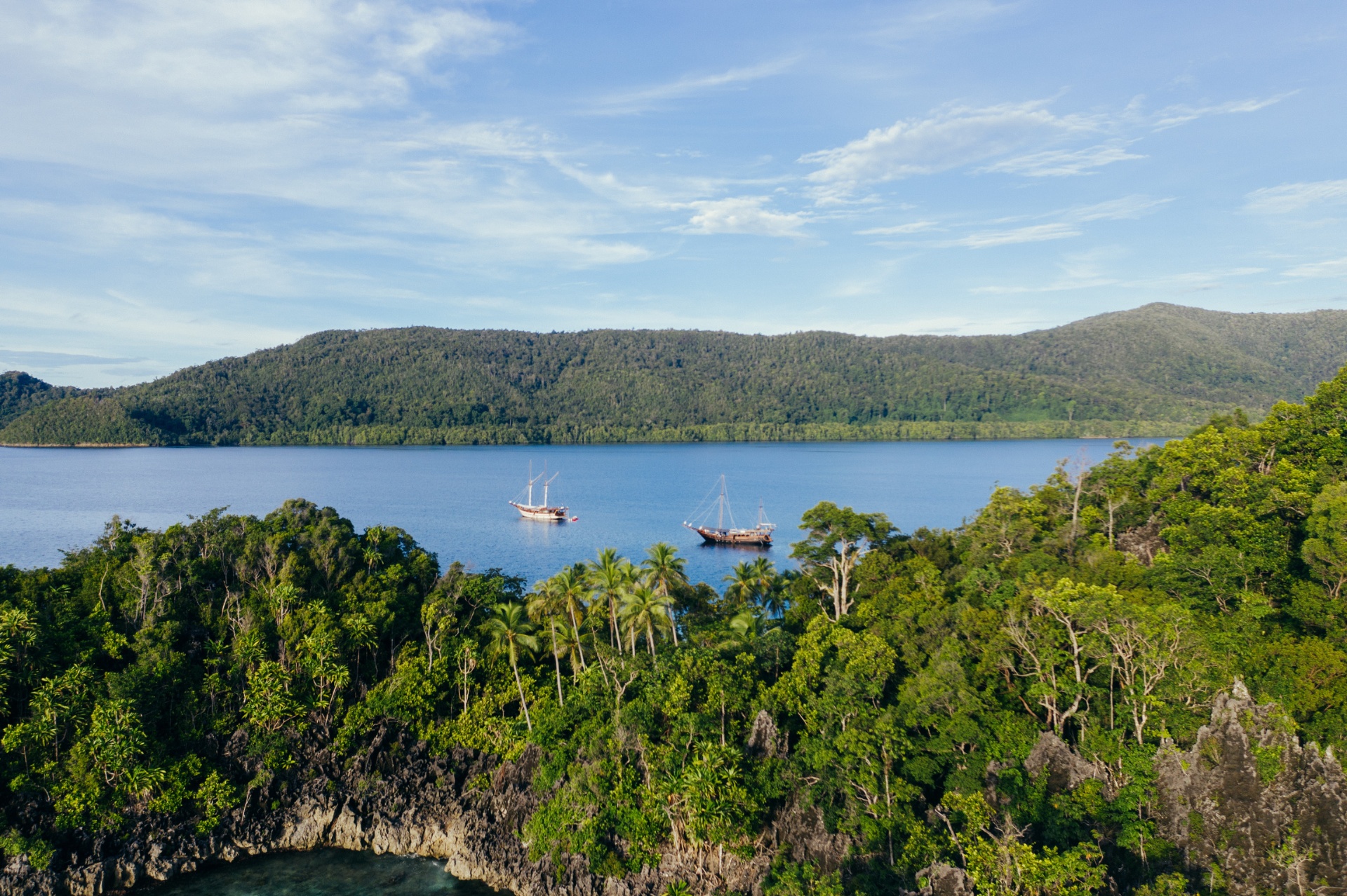 Senja and a second phinisi anchored in a jungle-lined bay in Raja Ampat