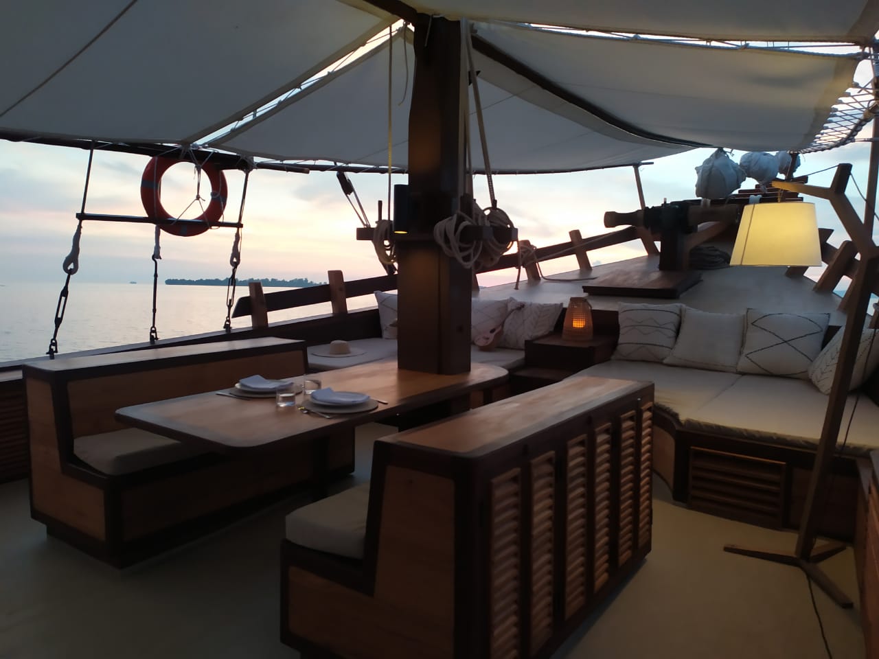 Table set for two on Senja's foredeck at sunset with pastel sky and lantern glow