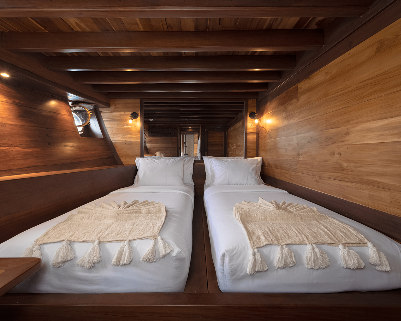 Sanya twin guest cabin with matching beds, exposed beams and warm timber walls