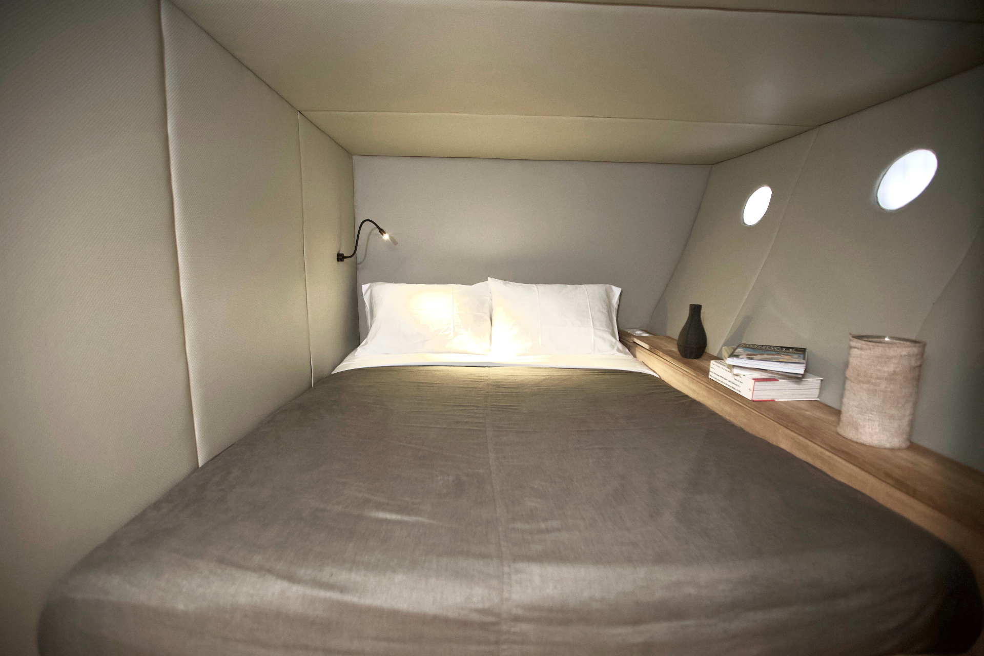 Splendour guest cabin with double bed, grey linen, reading light and twin portholes