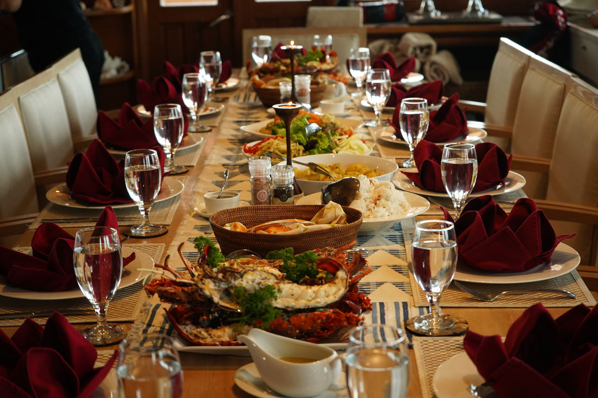 Lobster and Indonesian dishes plated across Lamima's saloon table for a shared feast