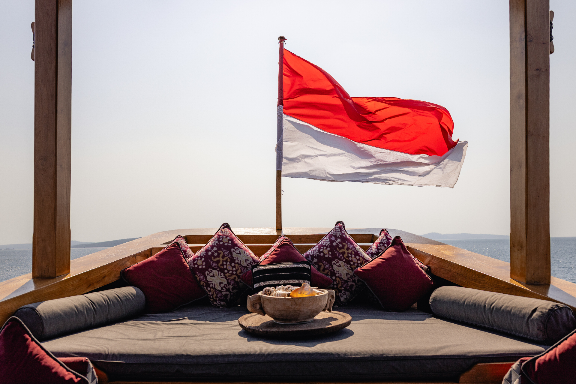 Bow daybed with ikat cushions and the Indonesian flag flying overhead