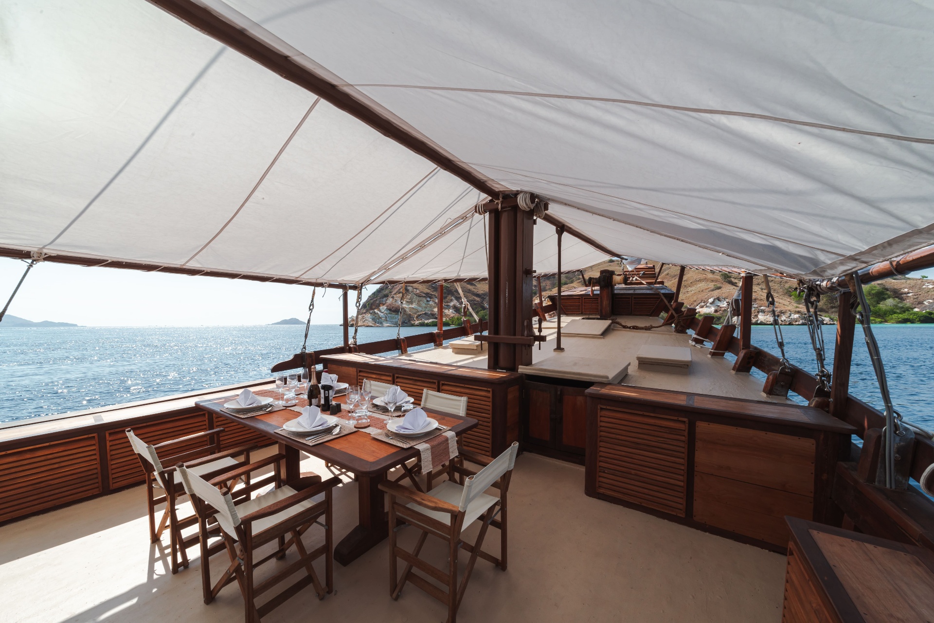 Shaded foredeck of Nataraja with dining table set for four and open sea views