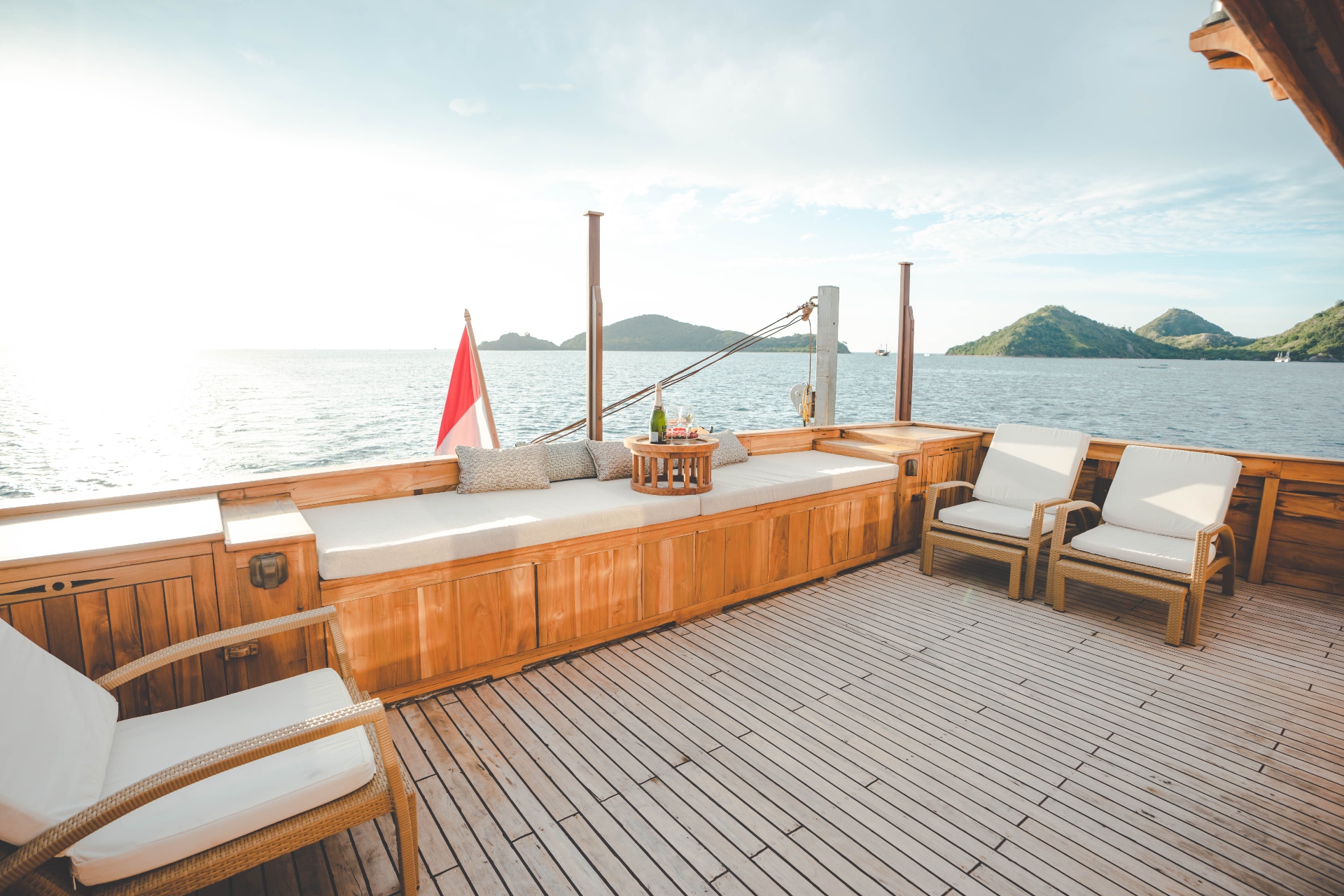 Mischief foredeck sun lounge with daybed, champagne setup, rattan armchairs and Komodo island views