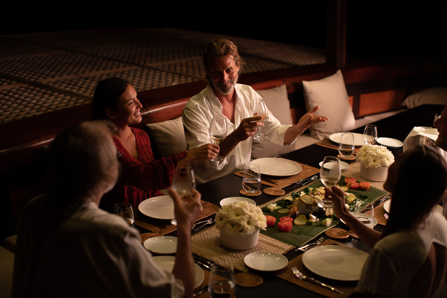 Guests toasting with white wine at a candlelit dinner on deck