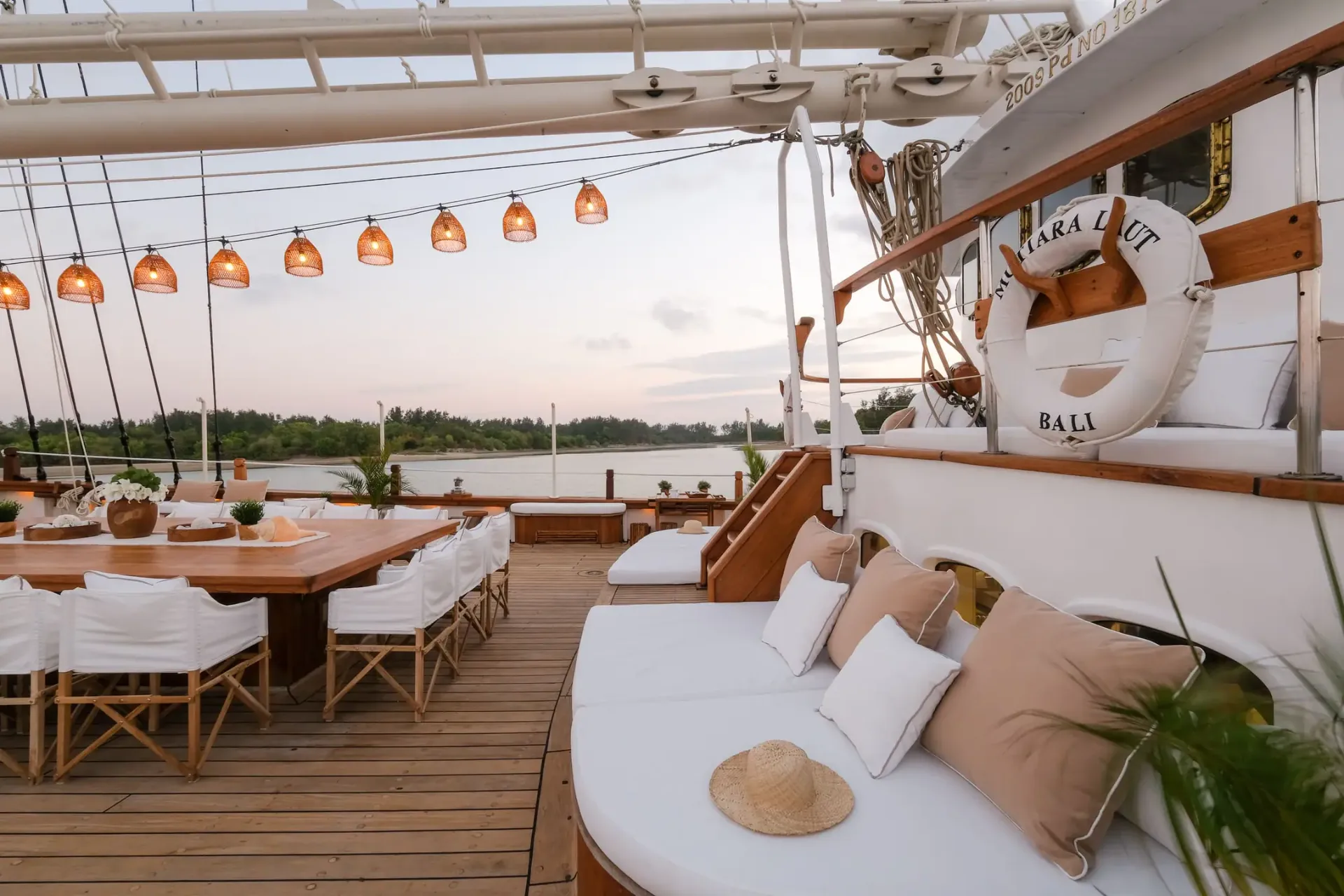 Mutiara Laut aft deck set for al fresco dining at sunset with rattan lanterns