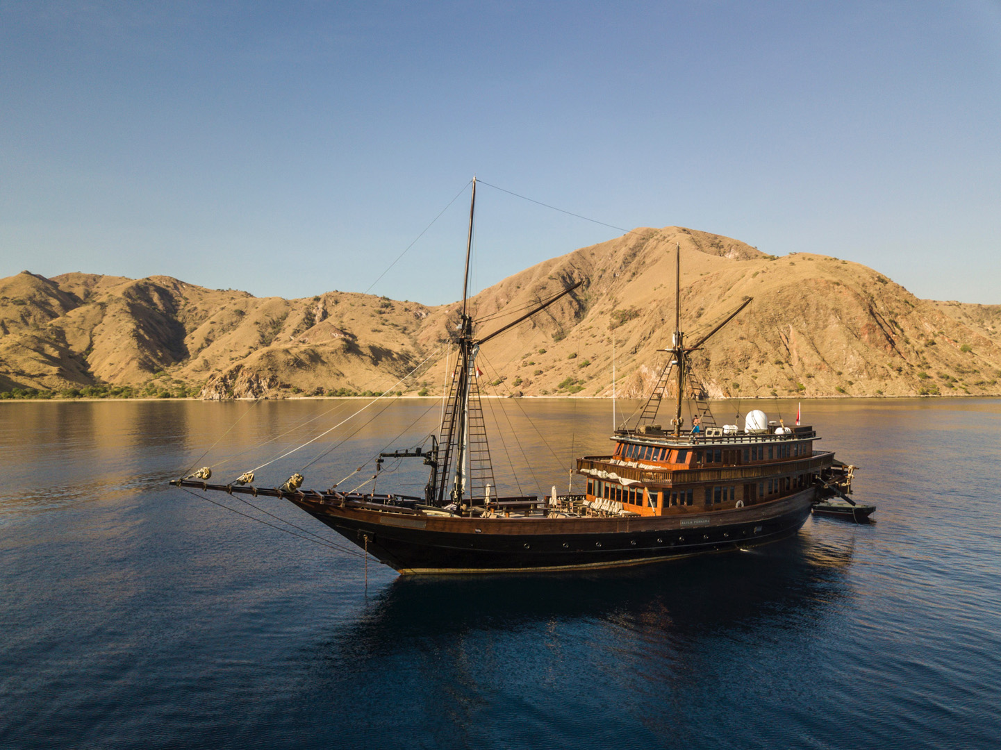 Aerial view of Alila Purnama anchored beside a dramatic Komodo hillside