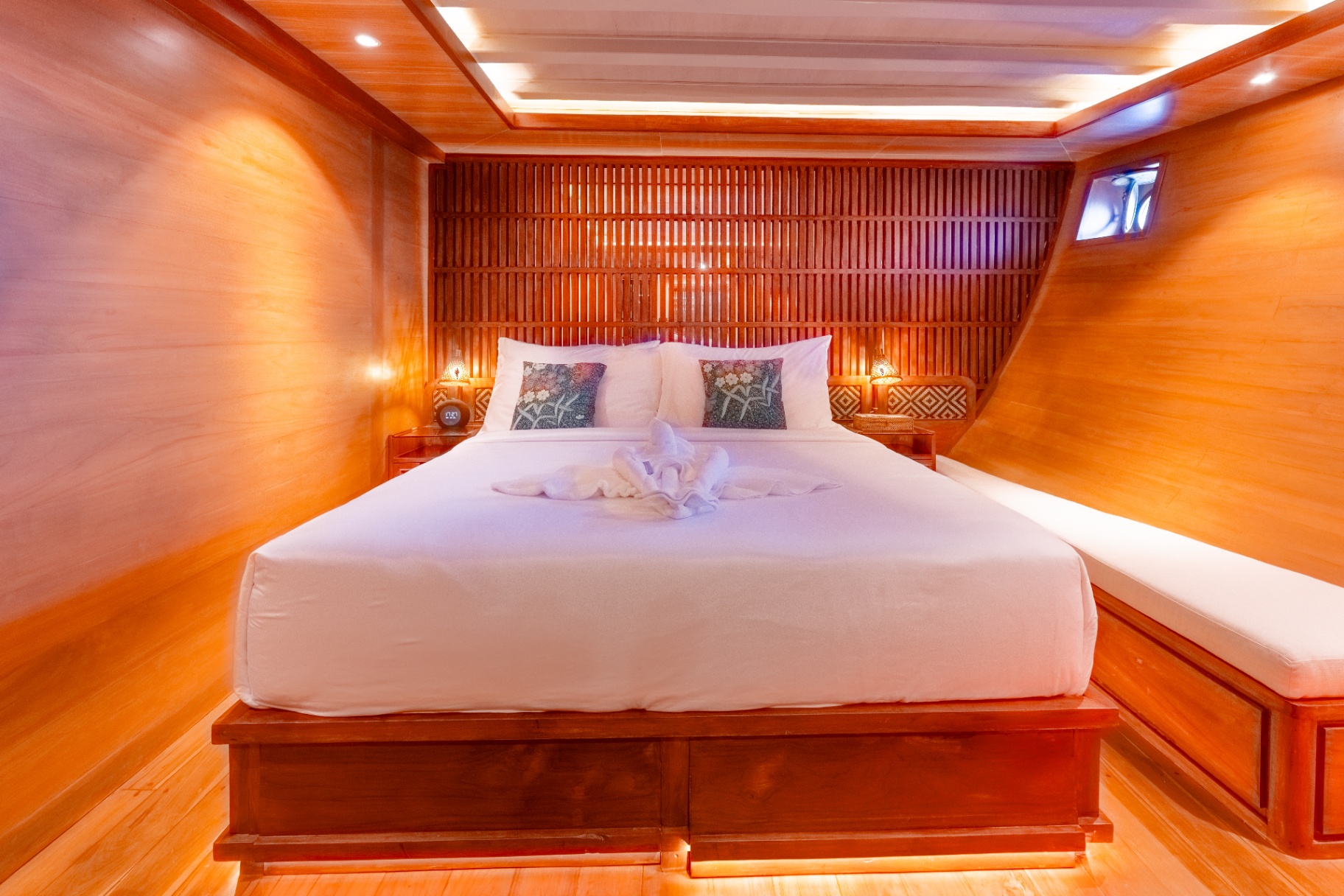 Lower-deck double cabin on Sanctuary with king bed, slatted teak headboard and warm accent lighting