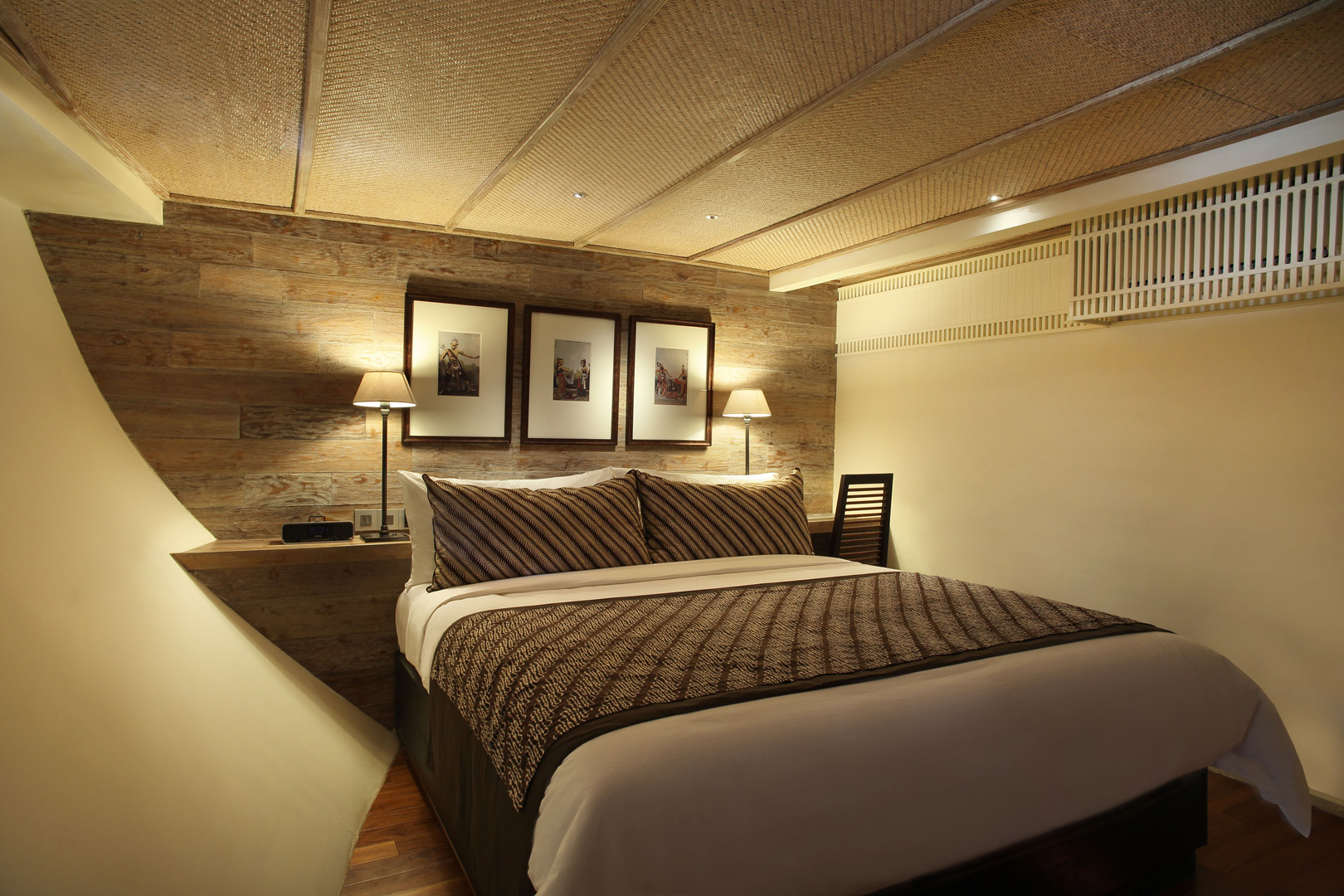 Jawa Suite on Alila Purnama with king bed, reclaimed teak headboard and framed heritage prints