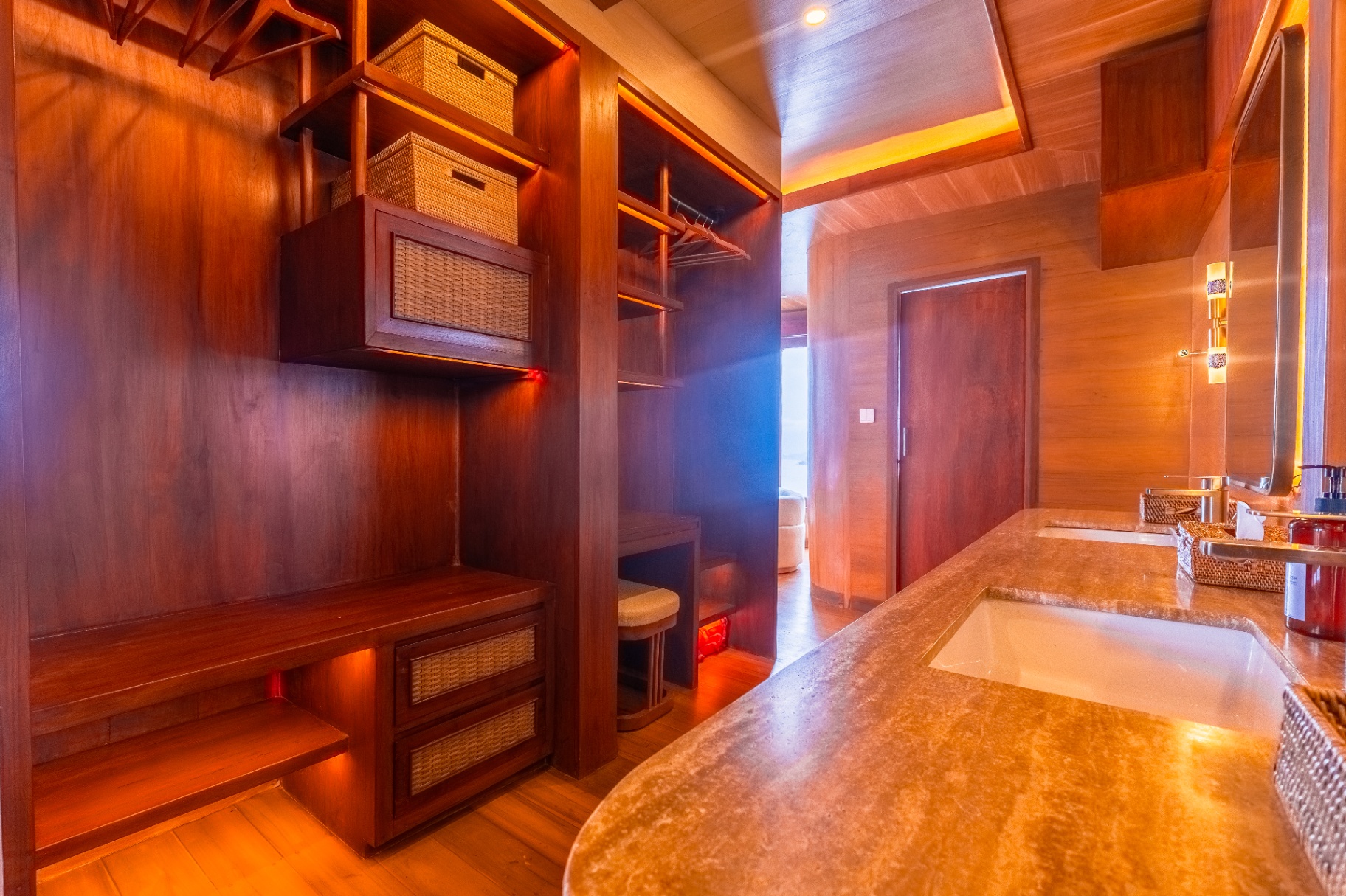 Walk-in wardrobe on Sanctuary's master suite with teak shelving, rattan storage baskets and a stone-topped vanity