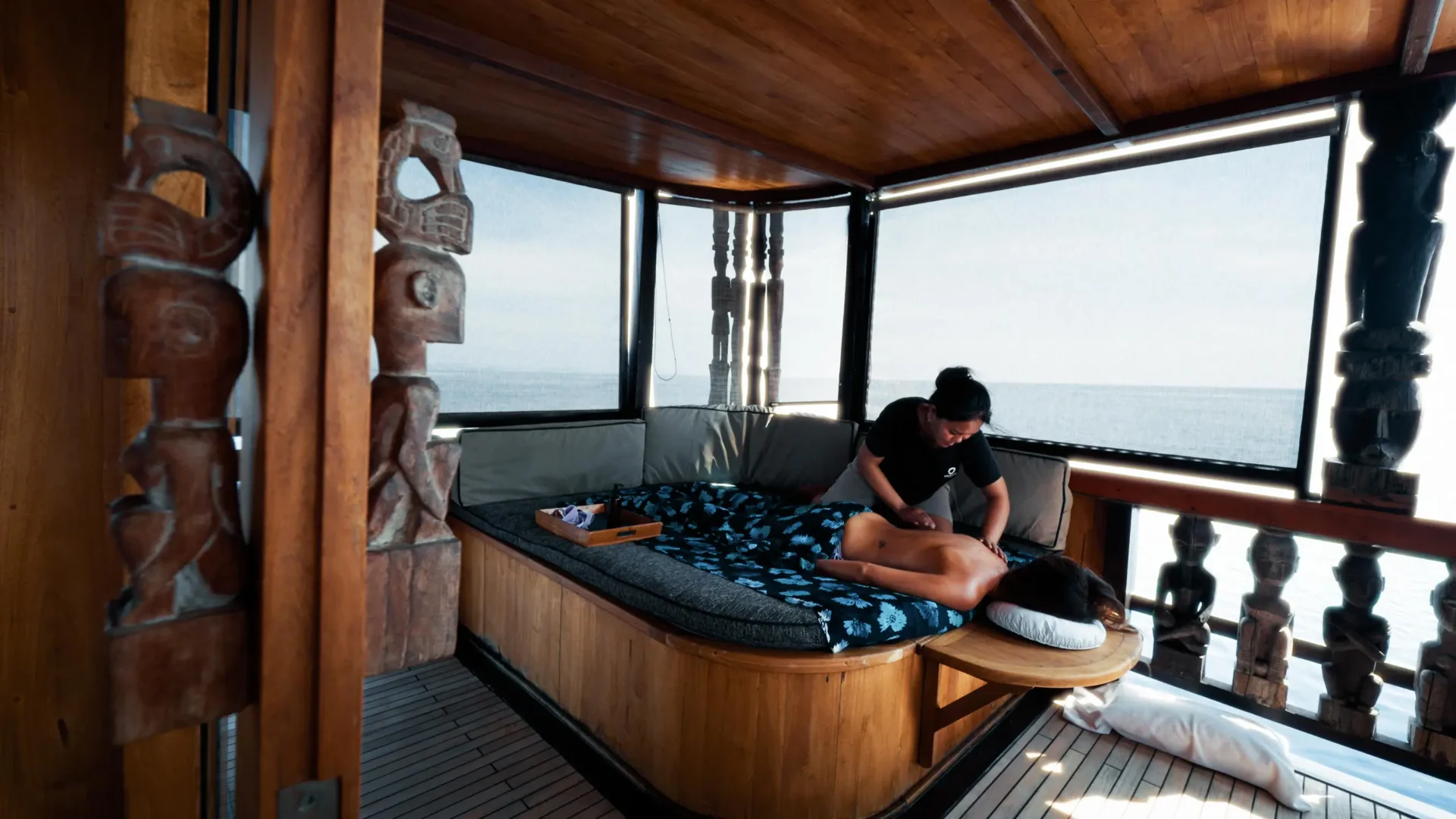 Massage being given on the upper deck of The Oracle with ocean view and tribal statues