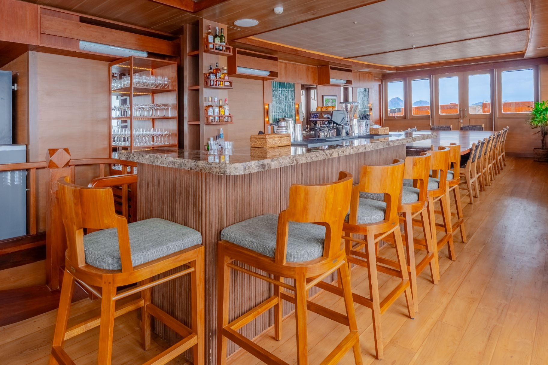 Long dining table beside the bar on Sanctuary set for group dinners with sea views through the windows