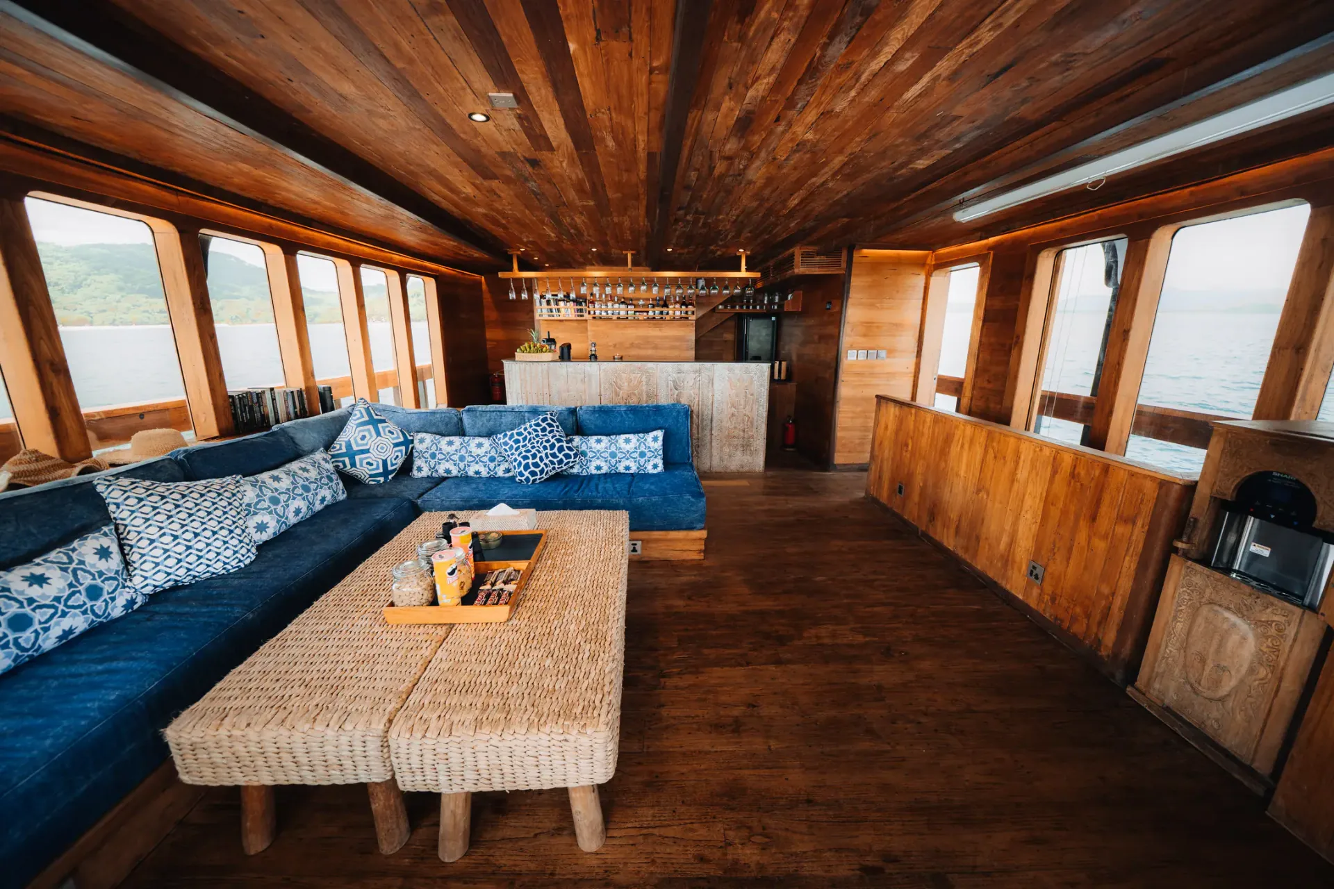 Main salon on The Oracle with indigo sofas, tribal carvings and a wooden bar