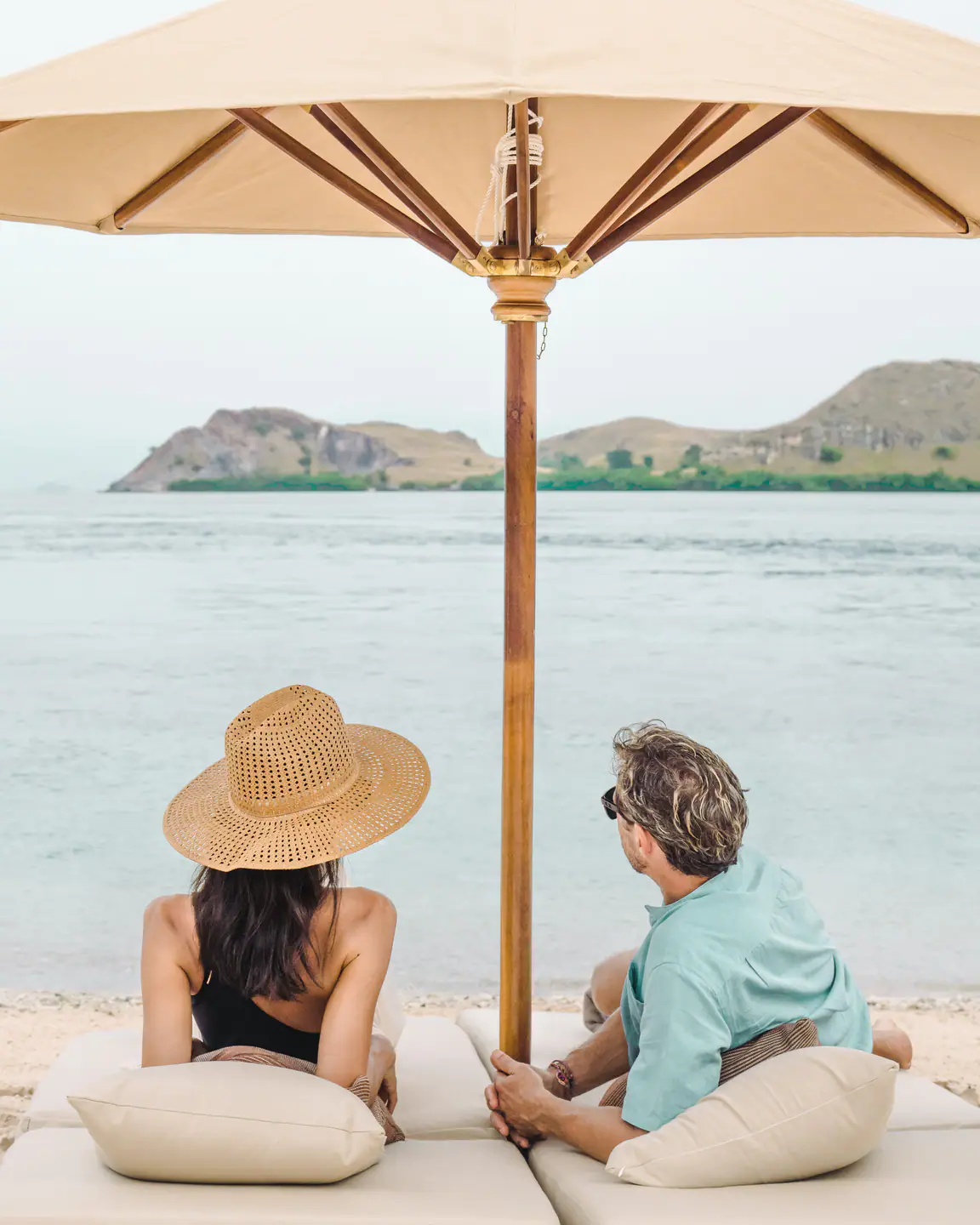 Couple relaxing on a private beach picnic setup from Celestia yacht charter