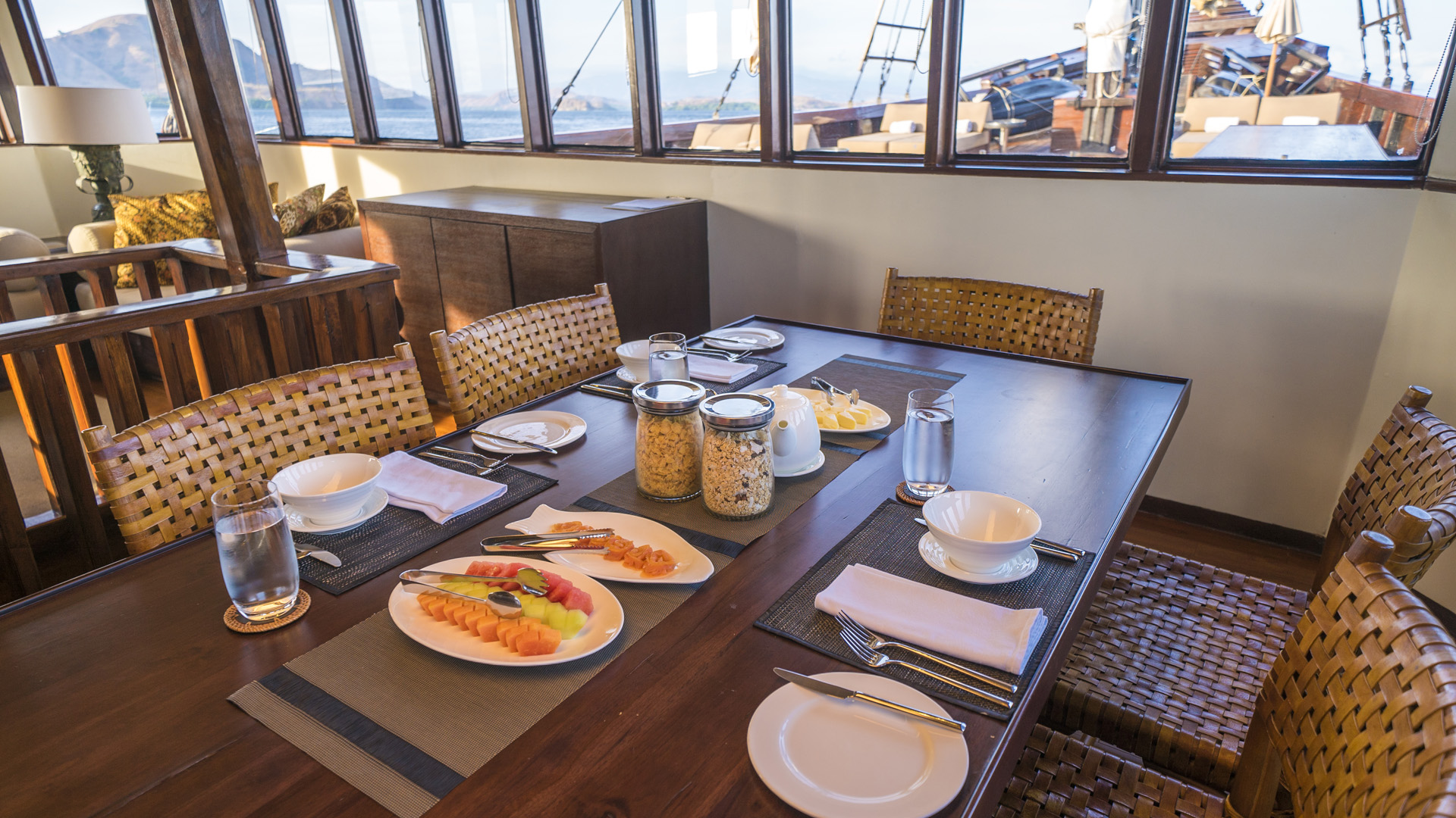 Indoor dining table on Alila Purnama set for breakfast with woven leather chairs and sea view