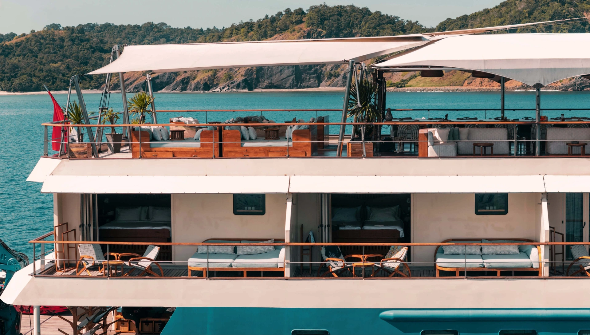 Side profile of Kudanil Explorer showing balcony cabins and shaded top-deck lounge
