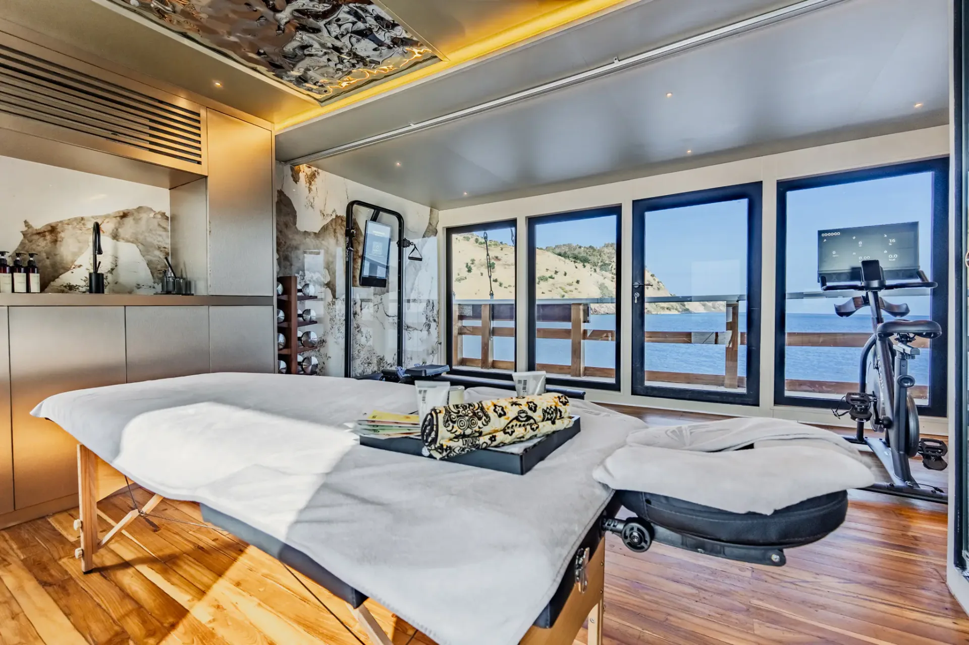 Spa treatment room on Kayra with massage bed, sculpted ceiling and panoramic sea view