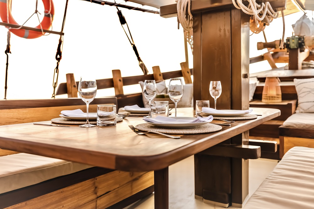 Close-up of Senja's foredeck dining table set with wine glasses, water and folded linen napkins at sunset