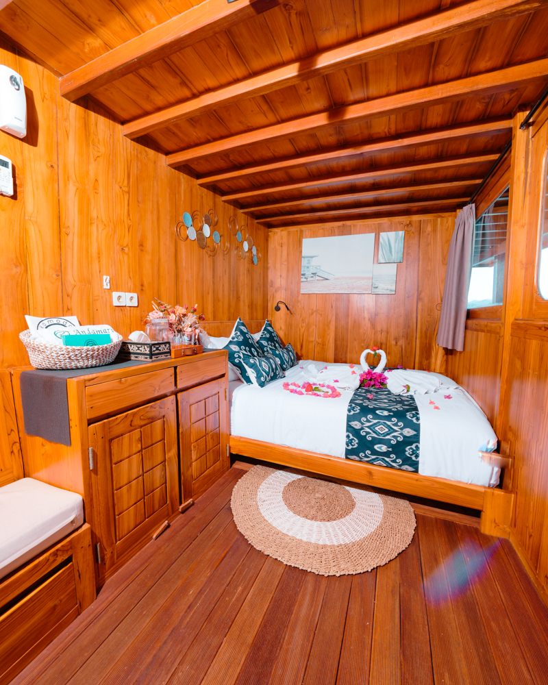 Portrait view of an Andamari double cabin with teak walls, woven rug and flower-styled bed
