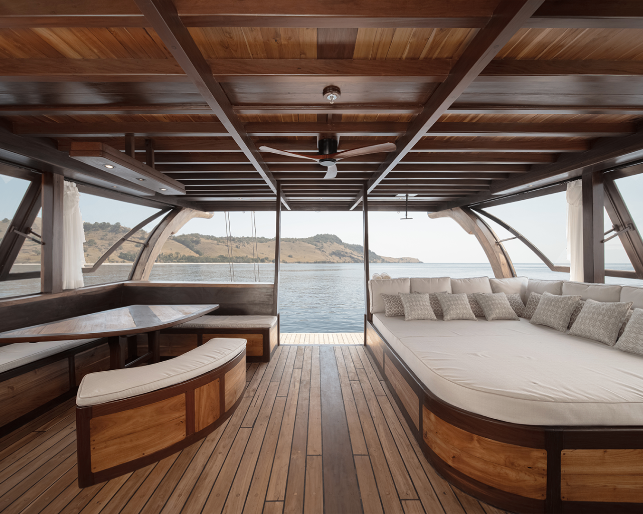Sanya aft deck lounge with large daybed, dining nook and open view of Komodo