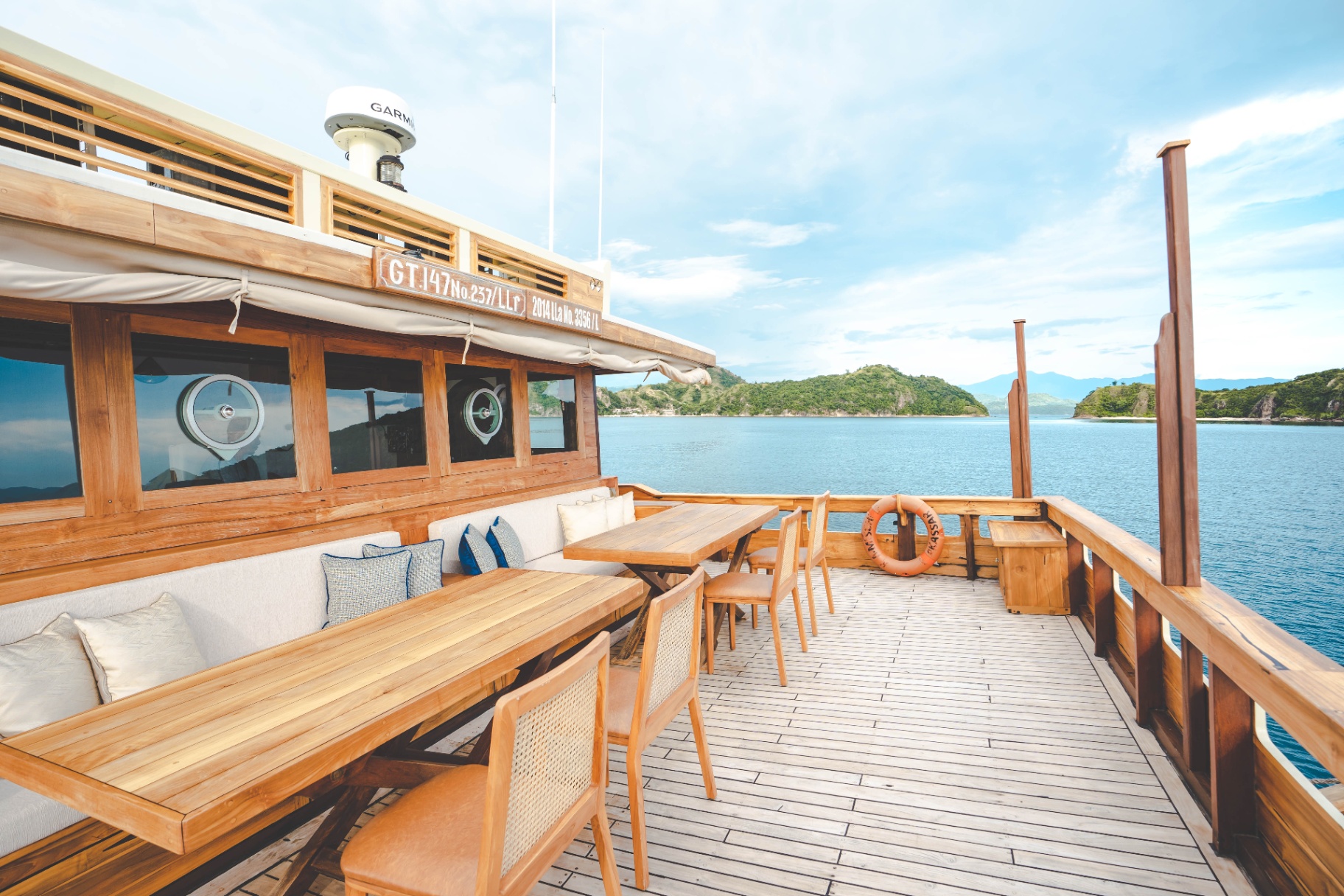 Mischief upper-deck alfresco dining area with teak tables, cane chairs and panoramic sea views