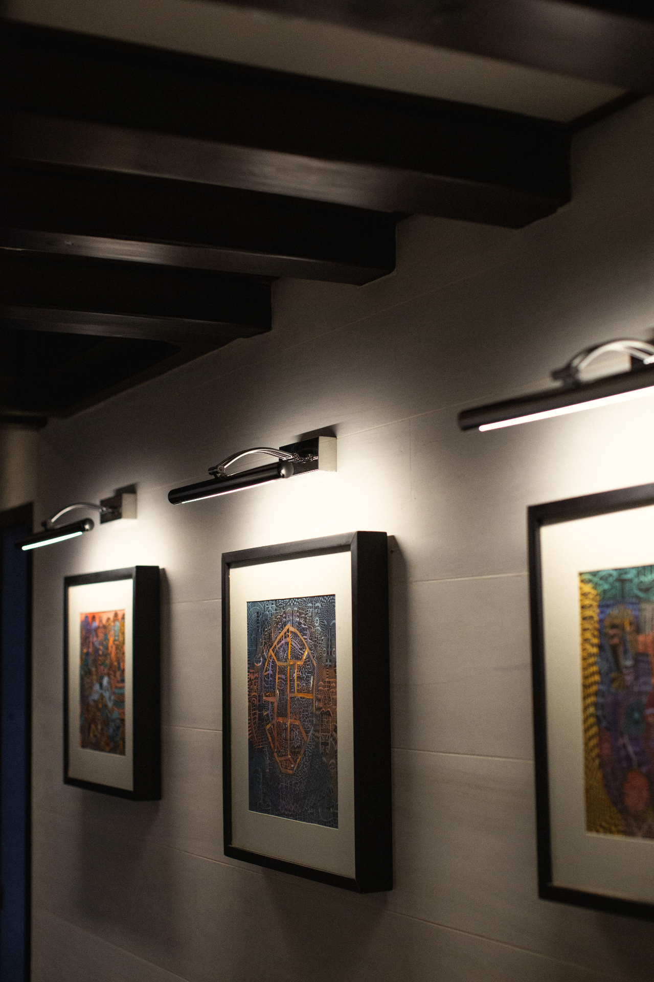 Lower deck staterooms corridor on Vela with framed Indonesian art and picture lights under exposed dark timber beams