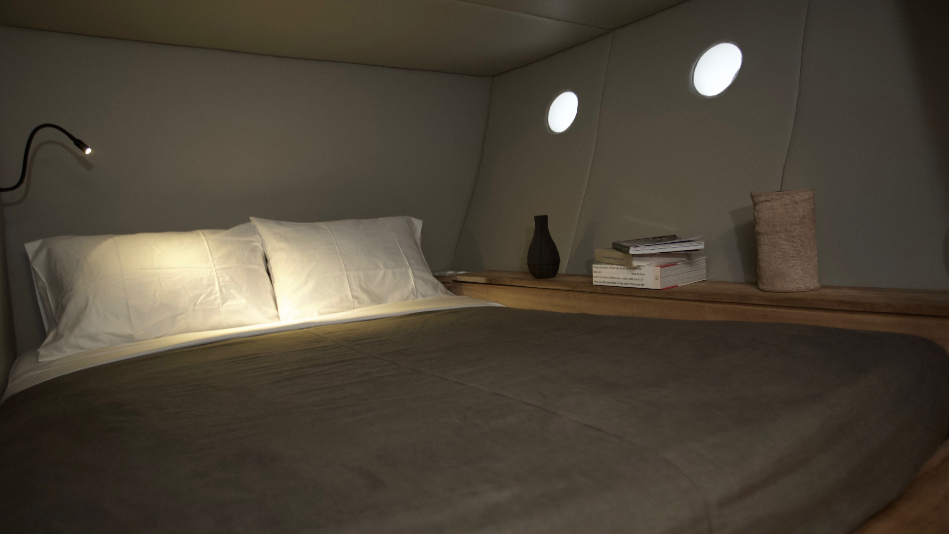 Splendour cabin interior with grey bedding, timber shelf, portholes and reading light