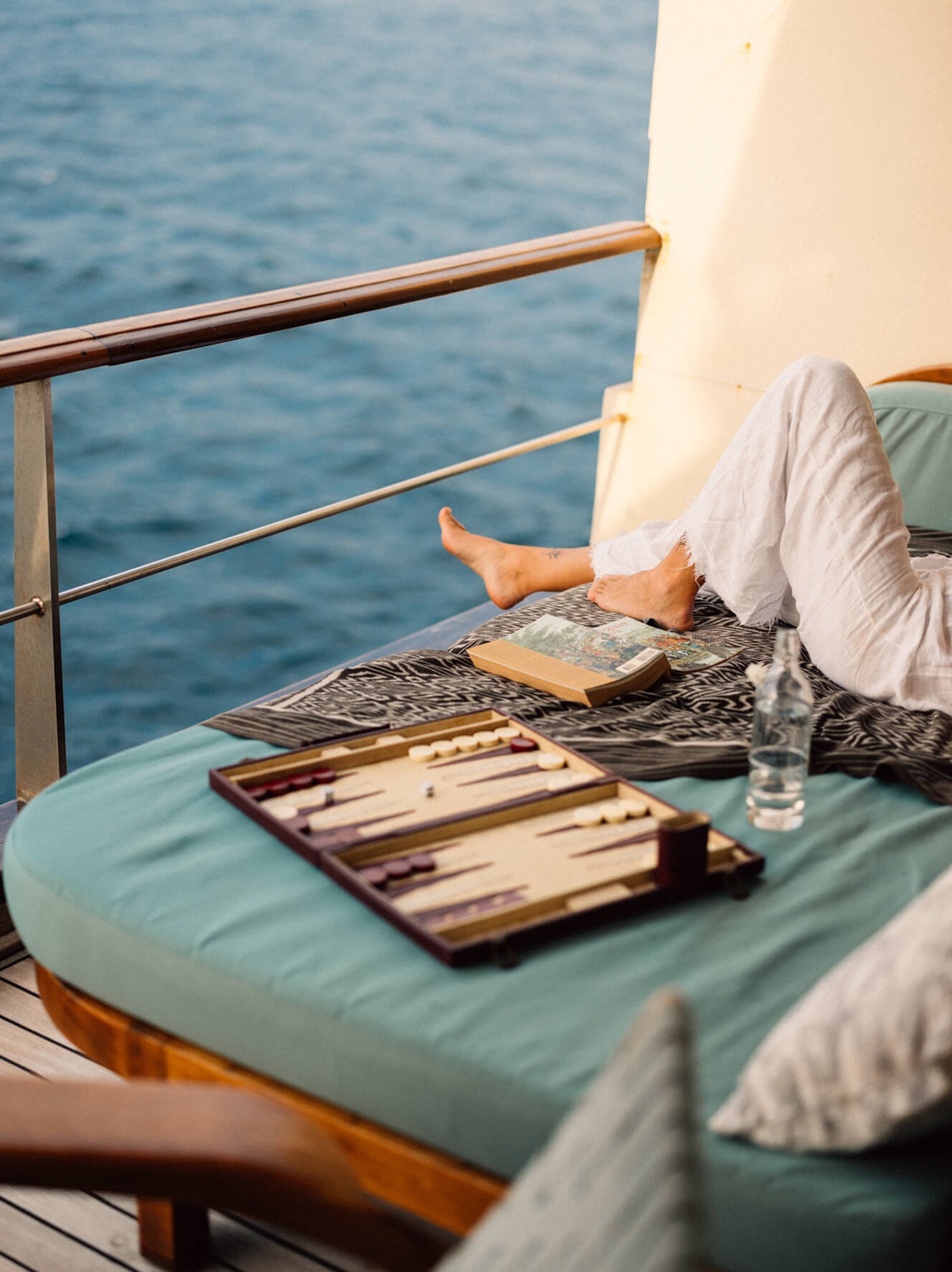Guest reading on a day bed with backgammon board, overlooking the sea from Kudanil Explorer