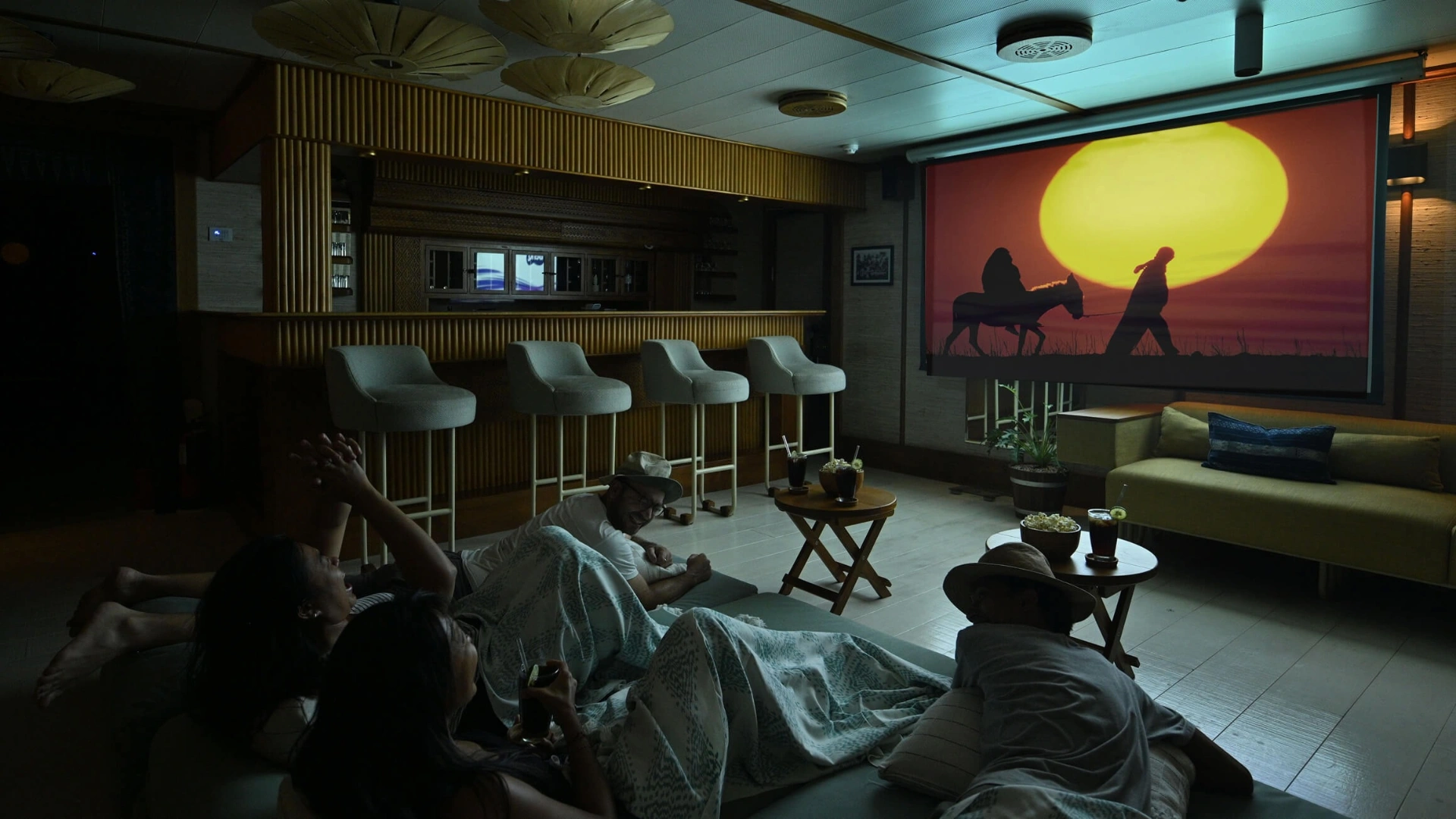 Guests watching a film in Kudanil Explorer's indoor cinema with popcorn and drinks