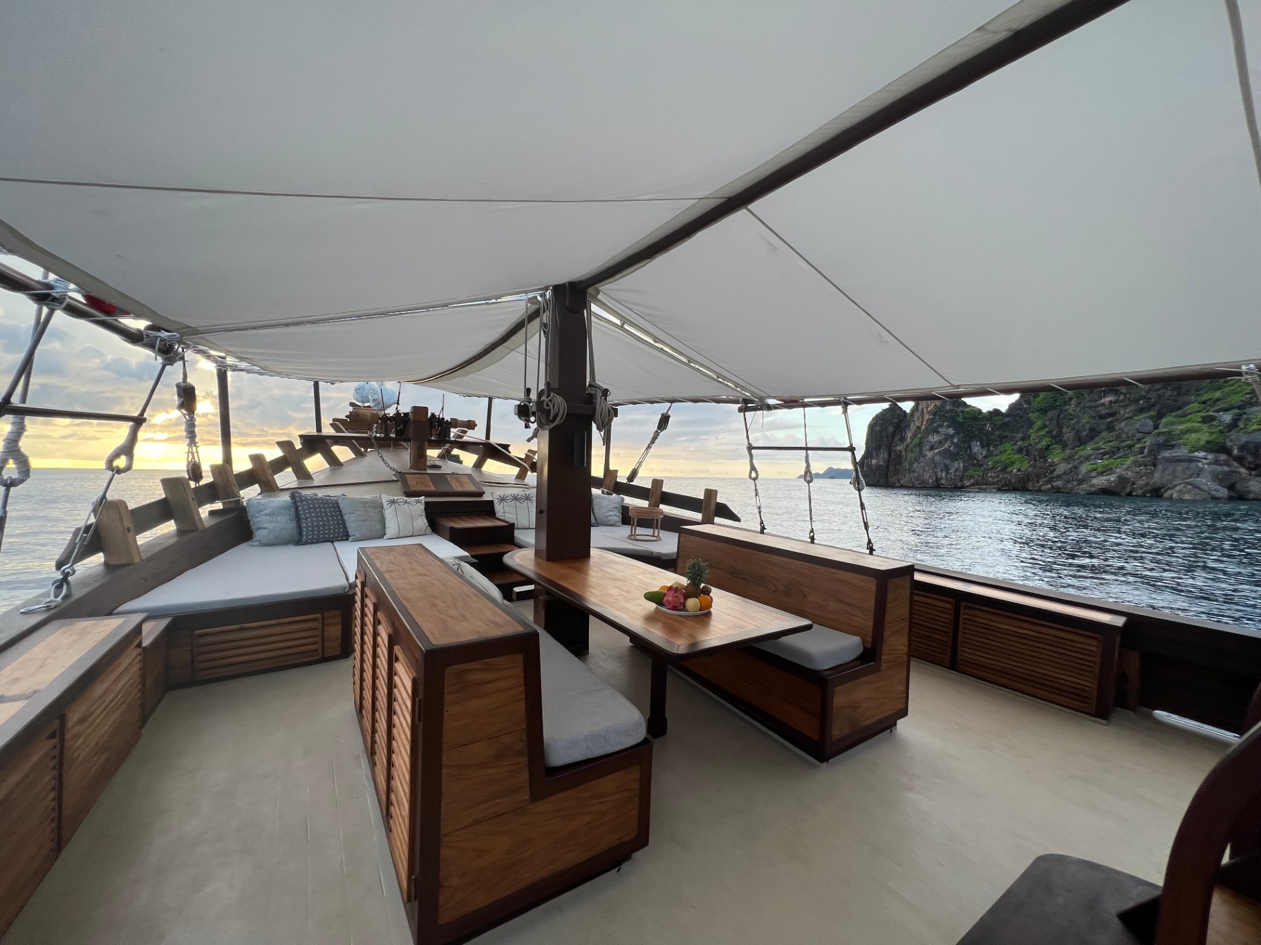 Dewata foredeck lounge and dining set against a karst cliff at sunrise