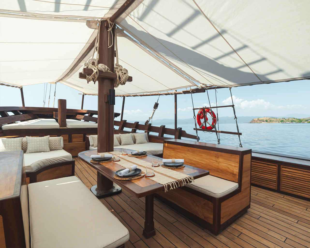 Shaded foredeck dining setup on Sanya with bench seating and open sea views