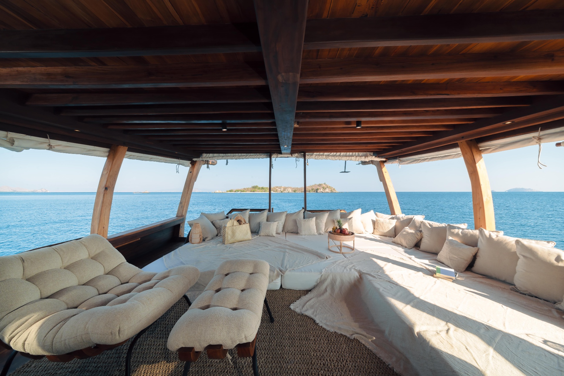 Aft deck chill lounge on Nataraja with cushioned daybeds, sofas and open sea views to a small island