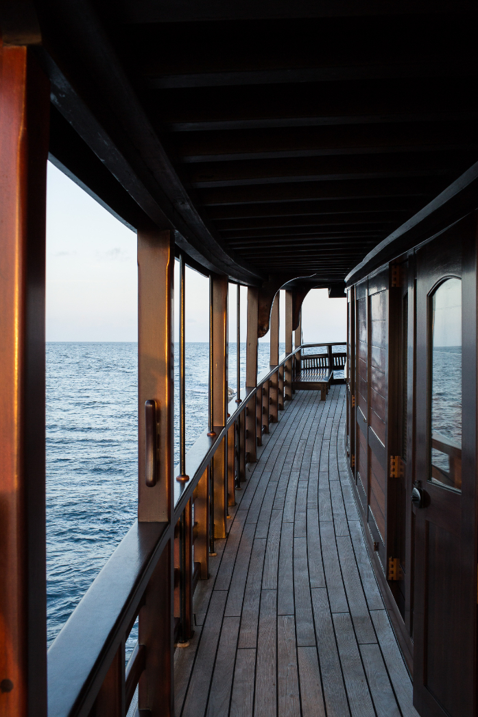 Teak side passage with polished wooden railings and ocean view